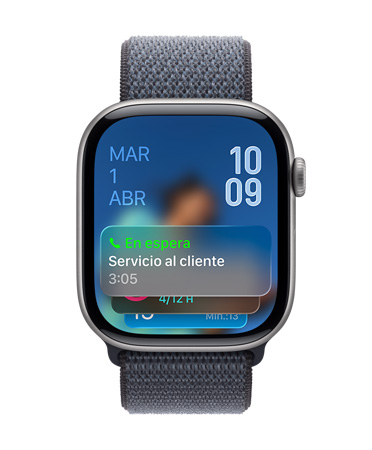 Apple Watch en negro azabache con una correa deportiva color salvia, cuya carátula muestra una notificación de Asistente de Llamada en Espera en la parte inferior, la fecha en la esquina superior izquierda, con la hora en números angostos en la esquina superior derecha