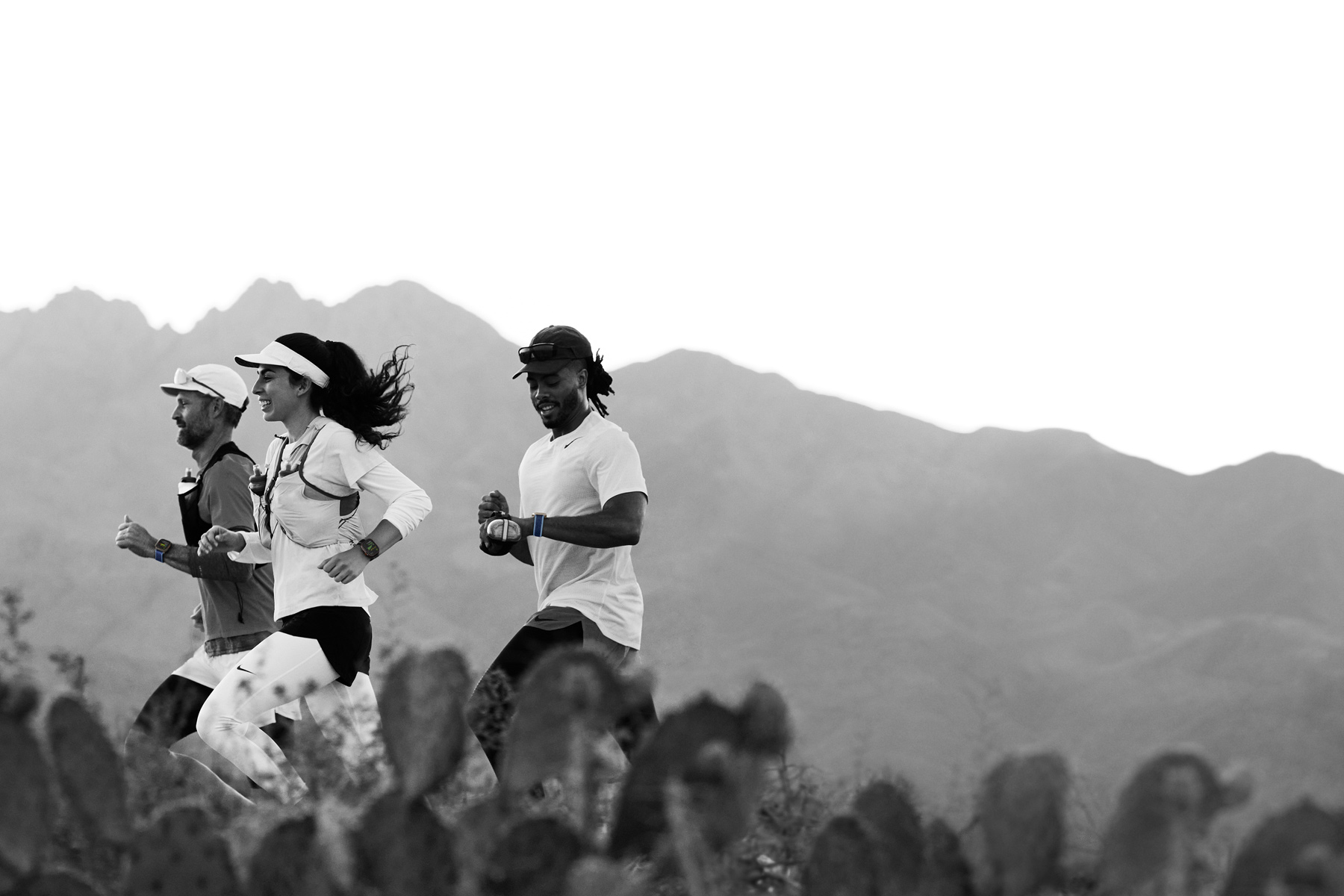 Három futó sivatagi terepen, mindannyian Apple Watch Ultra 3-mal mérik az edzésüket