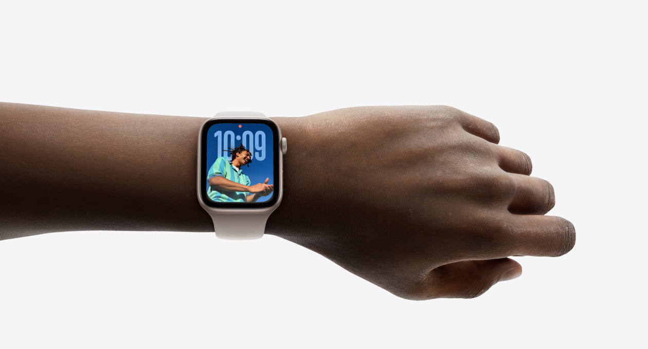 Close-up of Apple Watch in Rose Gold with rubber band on a person’s wrist, showing Time app in new Liquid Glass design
