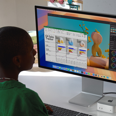 Una mujer trabaja en una hoja de cálculo de Excel en una Mac, sentada en una mesa de trabajo. La hoja de cálculo de Excel es un rastreador de ventas del cuarto trimestre. Detrás de la ventana con la hoja de cálculo de Excel hay una ventana de Pixelmator Pro.