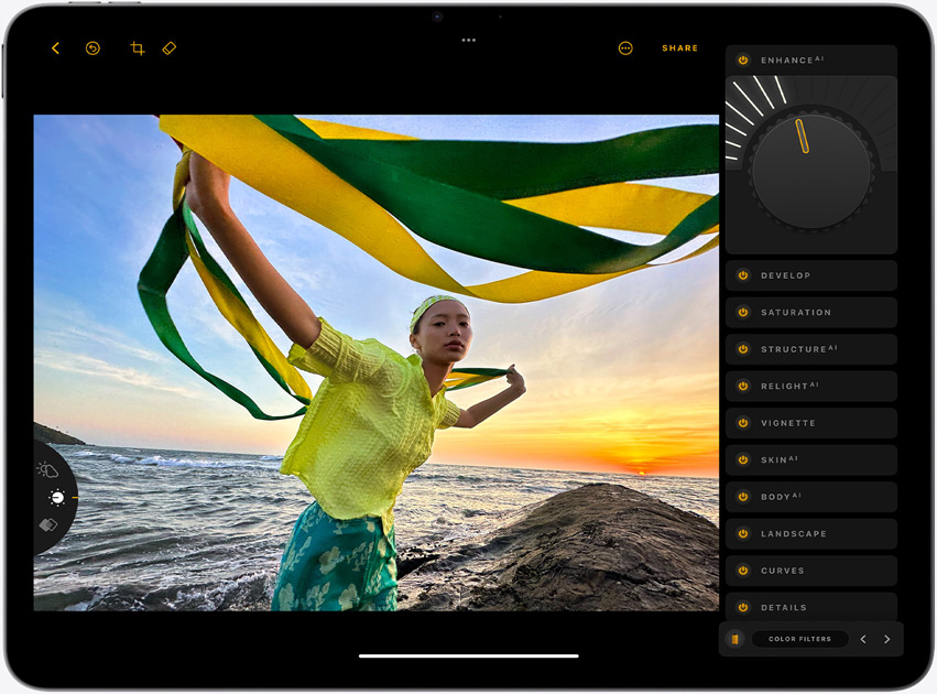 iPad Air, landscape orientation, screen displays a photograph of a girl holding yellow and green strands, standing in front of a sunset over the sea