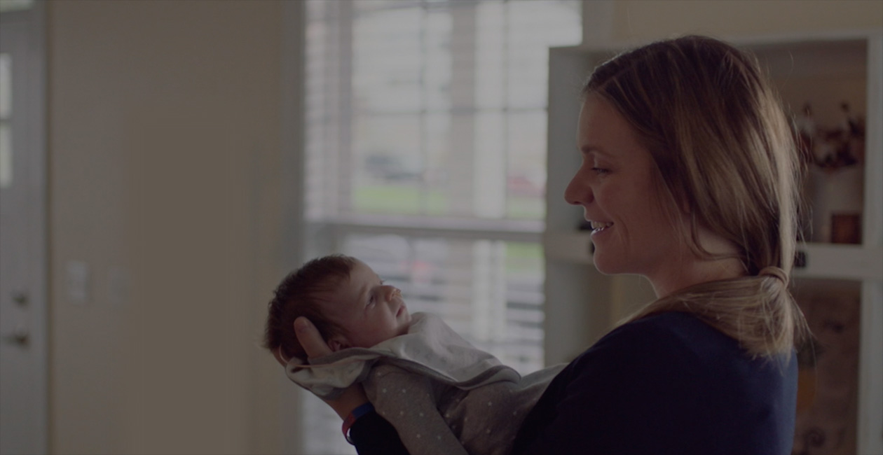 Een moeder kijkt lachend naar haar pasgeboren baby.